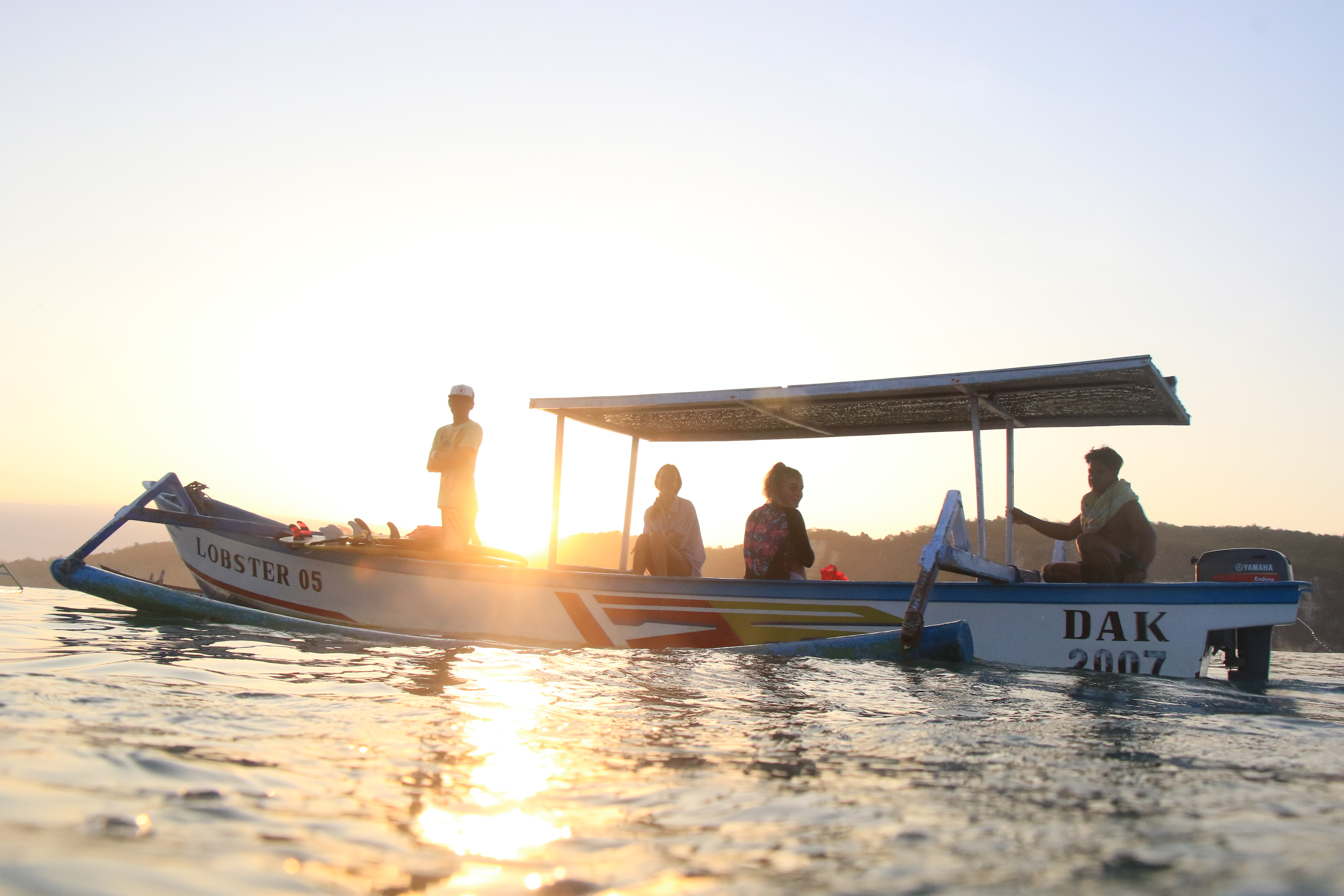 A boat heading out across the water at sunset