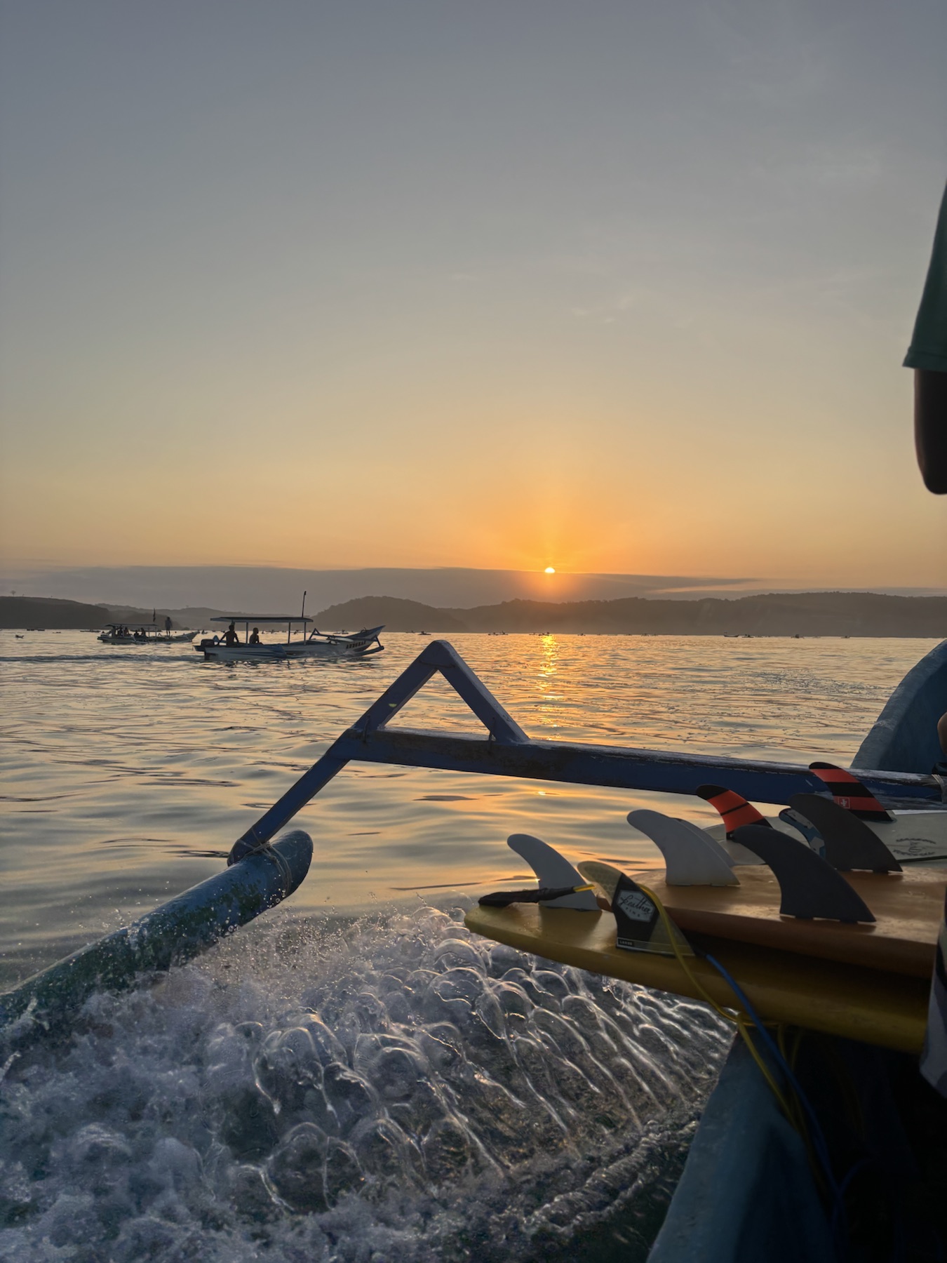 Sunset over the water with a surfboard on the boat
