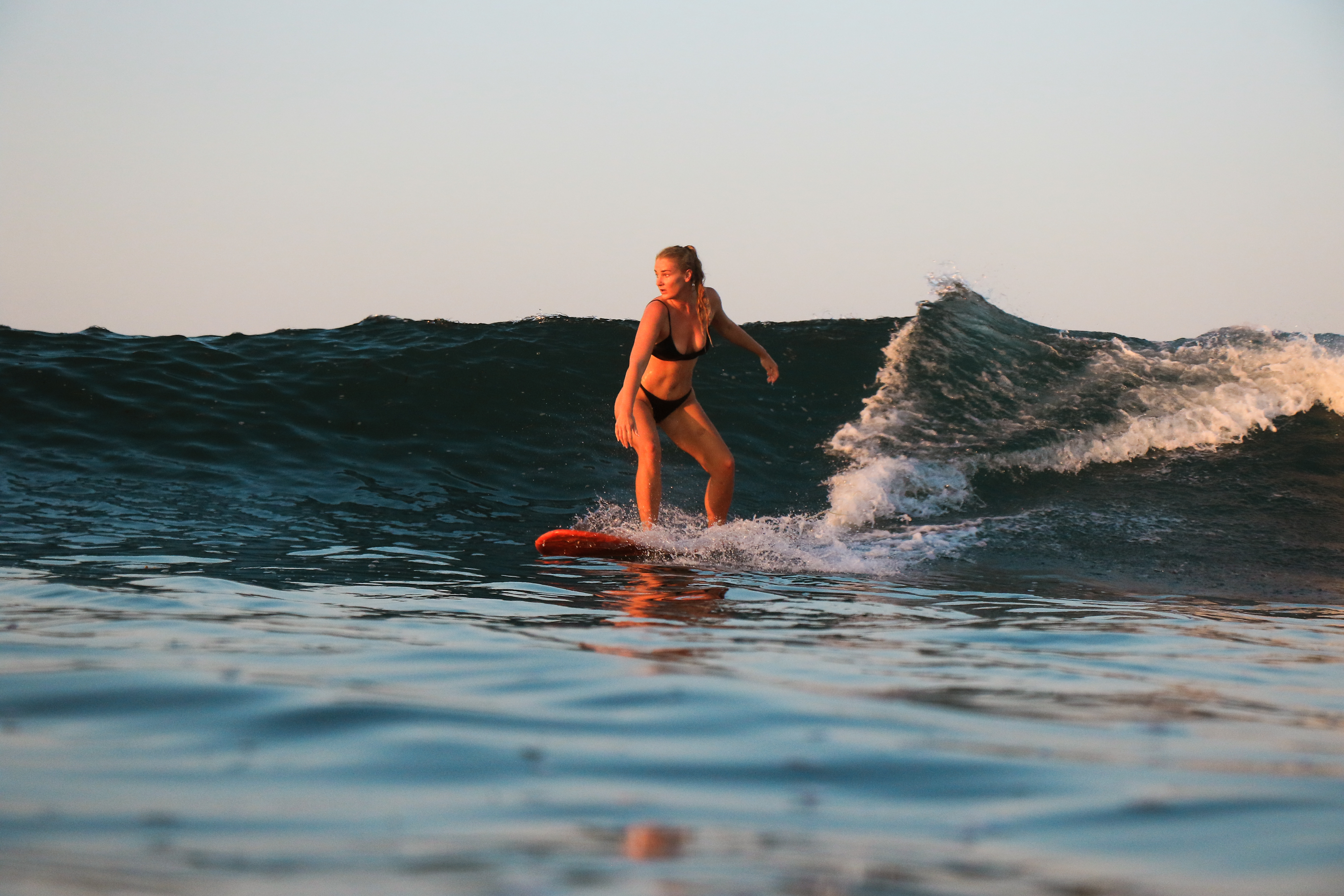 A surfer riding one of the waves at sunset